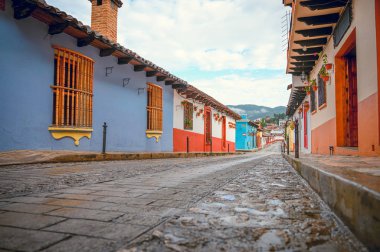Meksika 'nın San Cristobal De Las Casas şehrinin renkli caddesi Chiapas' ta, arka planda ağaçlık dağlar ve bulutlu bir gökyüzü