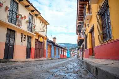 Meksika 'nın San Cristobal De Las Casas şehrinin renkli caddesi Chiapas' ta, arka planda ağaçlık dağlar ve bulutlu bir gökyüzü