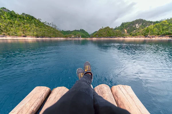 Mountain boots. A person sailing and wearing boots on a wooden raft in a turquoise river