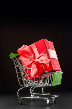 Alışveriş sepetinde saten fiyonk bulunan hediye paketi..