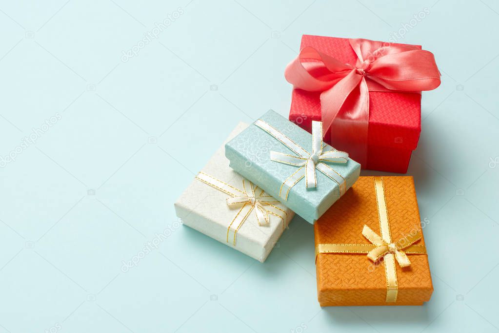 Small gift boxes are stacked on a pastel turquoise background. Christmas presents.