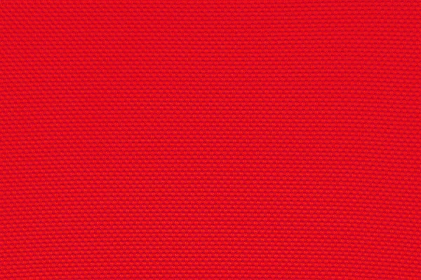 Fundo vermelho saturado profundo de uma matéria têxtil com padrão, close-up. pano de fundo perfurado . — Fotografia de Stock