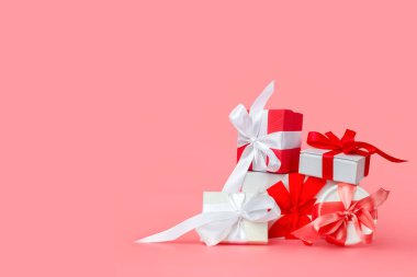 Pembe arka planda kırmızı saten kurdeleli beyaz hediye kutuları. Sevgililer Günü için bayram hediyeleri, Uluslararası Kadınlar Günü, düğün ya da nişan.