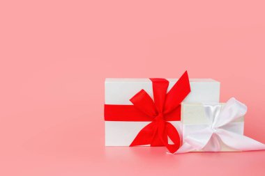 Mutlu Kadınlar Günü şablon tasarımı. Pastel pembe arka planda kırmızı fiyonklu dekoratif beyaz hediye kutusu.