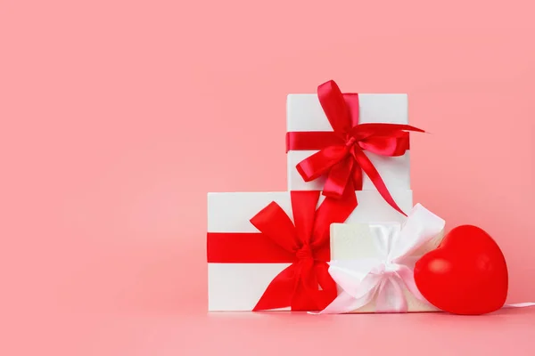 Design de modelo de dia feliz das mulheres. Caixa de presente branca decorativa com arco vermelho sobre fundo rosa pastel . — Fotografia de Stock