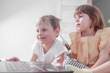 Küçük kız kardeşi, erkek kardeşiyle online uzaklık dersi izliyor. Sosyal uzaklık karantinası, kendini izole etme, covid-19 salgını sırasında evde eğitim. Dizüstü bilgisayarda çocuğun ödevi..