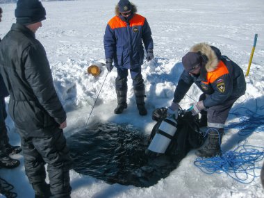 Baykal Gölü, Rusya - 12 Mart 2020: Kurtarma dalgıçları Baykal Gölü 'nde eğitim kampları düzenlediler. Profesyonel dalış ekipmanlarıyla dalgıçlar buzun altına, soğuk suyun altına dalmaya hazırlanıyorlar. Açık hava, kış.