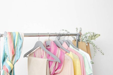 Bahar modası - Pastel renkli elbiseler raylarda. Beyaz arka plandaki askıların üzerinde renkli, parlak bahar giysileri. Giyim mağazası konseptinde indirim..