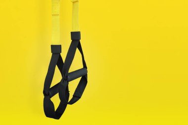 Kayışlar eğitim döngüsü. Sarı arka planda fonksiyonel eğitim ekipmanları. Spor aksesuarları.