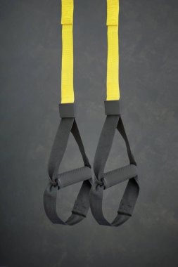 Kayışlar eğitim döngüsü. Sarı arka planda fonksiyonel eğitim ekipmanları. Spor aksesuarları.