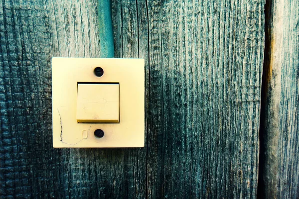 Interruptor de iluminación viejo en la pared de madera. Cierre la mano que enciende o apaga el interruptor de luz gris con fondo de madera. Copiar espacio . — Foto de Stock
