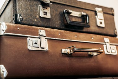 Antika siyah ve kahverengi bavullar bir rafta duruyor.