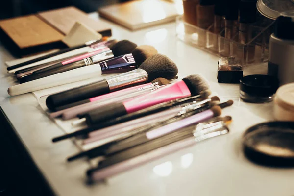 Op de tafel met een spiegel, zijn penselen, lippenstift, crème, mascara en haarlak — Stockfoto