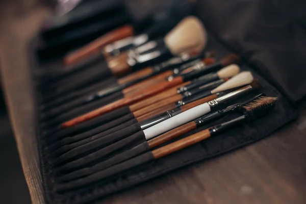 Makeup artist brushes in a case on a wooden table — ストック写真