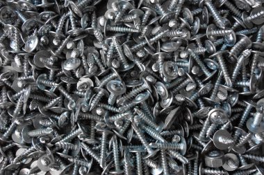 Masanın üzerinde bir sürü gri metal vida var. Yakın plan, arka plan.