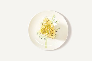 Beyaz arka planda beyaz bir tabakta ev yapımı taze kek dilimi. Yukarıdan yakın plan, minimalizm.