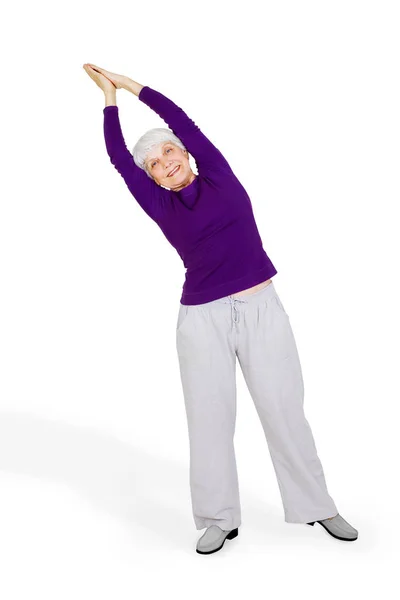 Счастливая очаровательная пожилая женщина, делающая упражнения во время занятий спортом. На белом фоне — стоковое фото