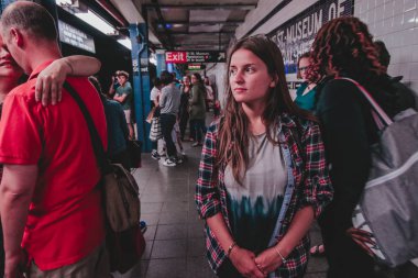 New York, Usa- 16 Haziran 2017: Manhattan 'daki Mta metro istasyonunda metro treni bekleyen kadın 8. caddede kalabalık bir metro platformu..