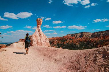 Hiker woman in Bryce Canyon hiking looking and enjoying view during her hike wearing hikers backpack. Bryce Canyon National Park landscape, Utah, United States. Sunny Day, clear skies, hot summer. clipart