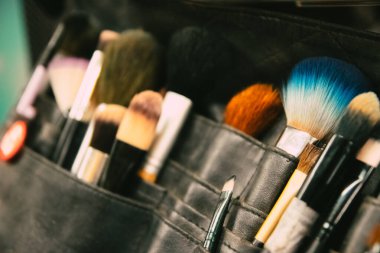 Makyaj çantasında çeşitli profesyonel makyaj fırçaları ve aletleri, renkli kozmetik ürünler.