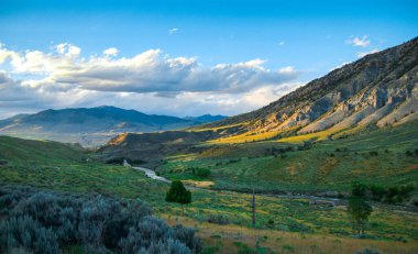 Yellowstone Ulusal Parkı 'nın güney kısmının güzel günbatımı manzarası. Dağ tepeleri yazın çimen ve ağaçlarla doludur. Altın saat.