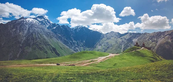 Beautiful Gergeti Trinity Church with mountain peaks covered in snow in the background on a sunny day. Holy Trinity Church near the village of Gergeti in Georgia, under Mount Kazbegi