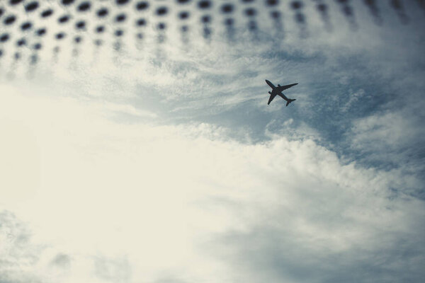The plane in the cloudy sky, view from a window if a car, down shot. Copy space. Travel, destination concept.