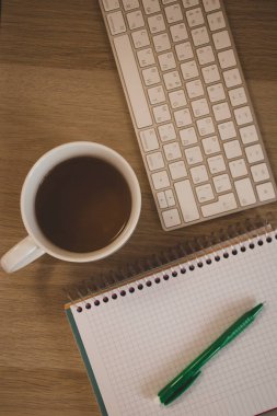 defter ve kupa ahşap masada.