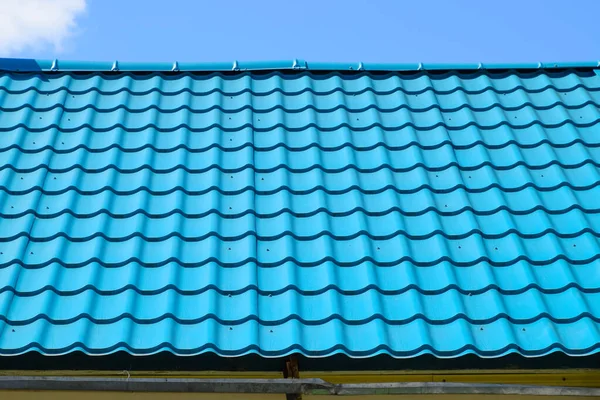 Turquoise metal tiles on the roof of the house. Modern roofing materials