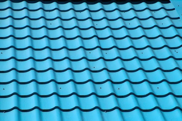 Turquoise metal tiles on the roof of the house. Modern roofing materials