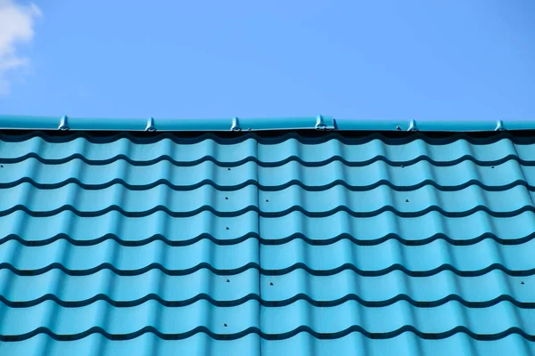 Turquoise metal tiles on the roof of the house. Modern roofing materials