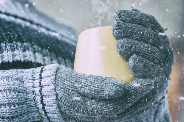 Mädchen in Fäustlingen hält eine Tasse heißen Tee im Schnee — Stockfoto