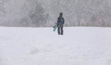 Elleri dağda, kar yağışı altında kar kayağı yapan bir kız.