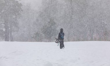 Elleri dağda, kar yağışı altında kar kayağı yapan bir kız.