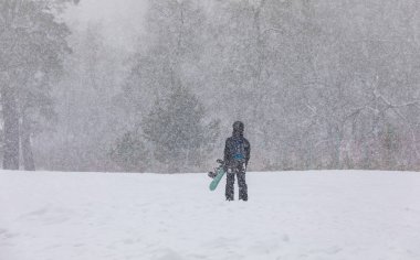 Elleri dağda, kar yağışı altında kar kayağı yapan bir kız.