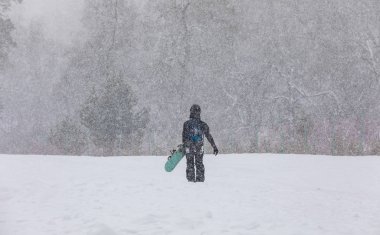 Elleri dağda, kar yağışı altında kar kayağı yapan bir kız.