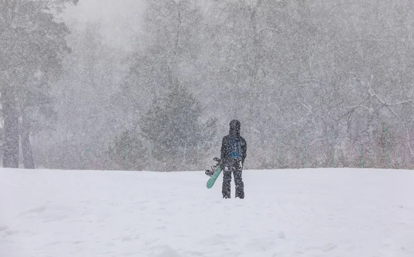 Elleri dağda, kar yağışı altında kar kayağı yapan bir kız.