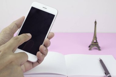 Defter, kalem ve Hediyelik eşya Eiffel ile akıllı telefon kullanan adam 