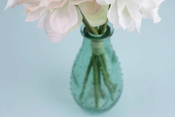 Hermosas flores en un jarrón verde sobre fondo azul . —  Fotos de Stock