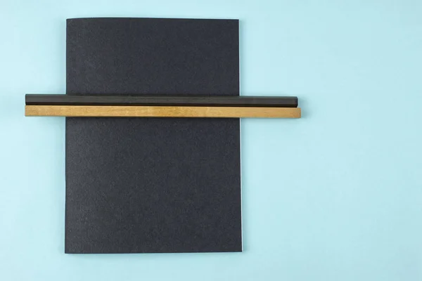 Caderno preto e lápis sobre fundo azul . — Fotografia de Stock