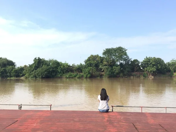 Mujer sentada a la orilla del río con filtro vintage . —  Fotos de Stock