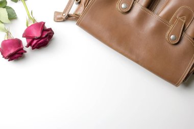 Gül beyaz arka plan üzerinde kahverengi deri çanta. 