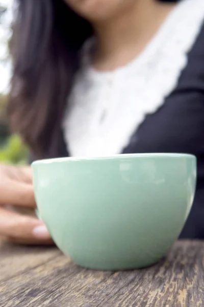 나무 테이블에 뜨거운 커피 한 잔을 들고 여자. — 스톡 사진