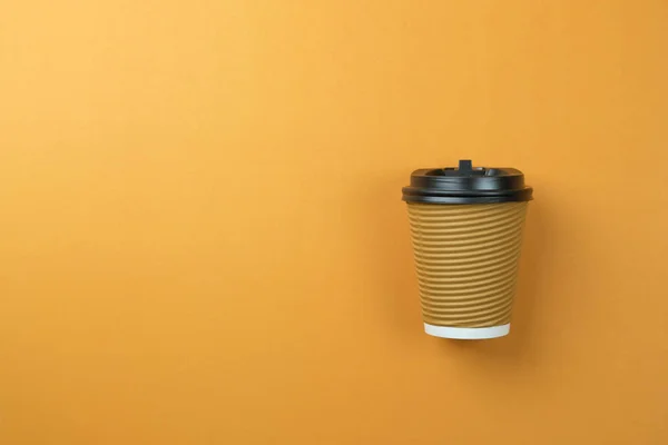 Sacar taza de café de papel sobre fondo naranja . — Foto de Stock