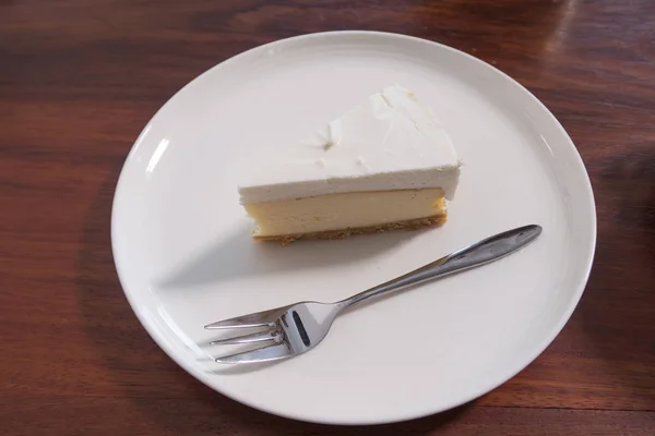 A piece of white cake and fork on white plate.