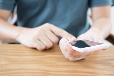 Ahşap masa üzerinde akıllı telefon kullanan adam.