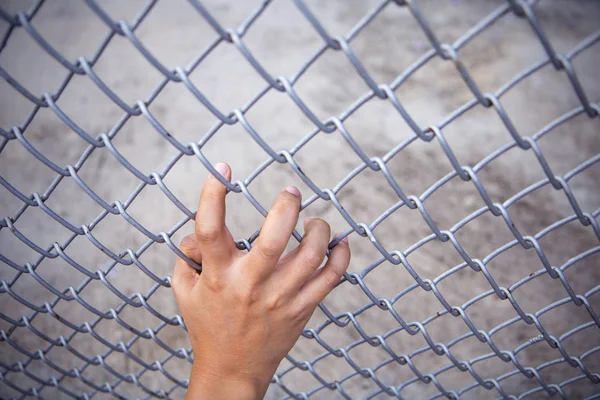 Man hand grabbing steel mesh cage. no freedom. Top view.