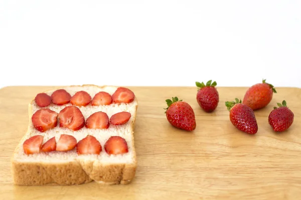 Pan integral y trozos de fresa en la tabla de cortar — Foto de Stock