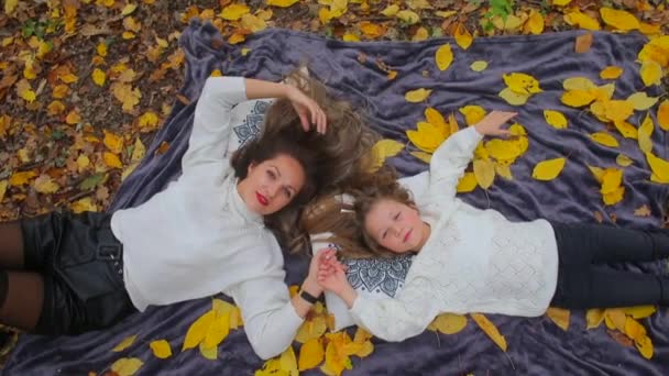 Mom and daughter lay on the ground in the autumn forest — ストック動画