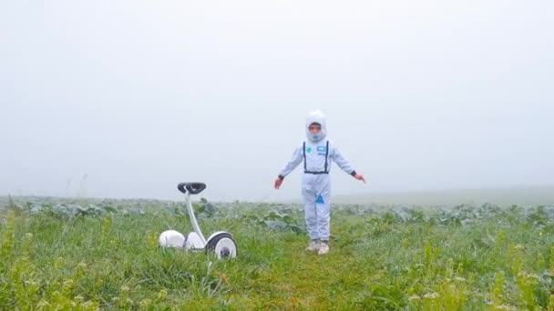 Мальчик астронавт стоит с распростёртыми руками в белом поле на плену — стоковое видео